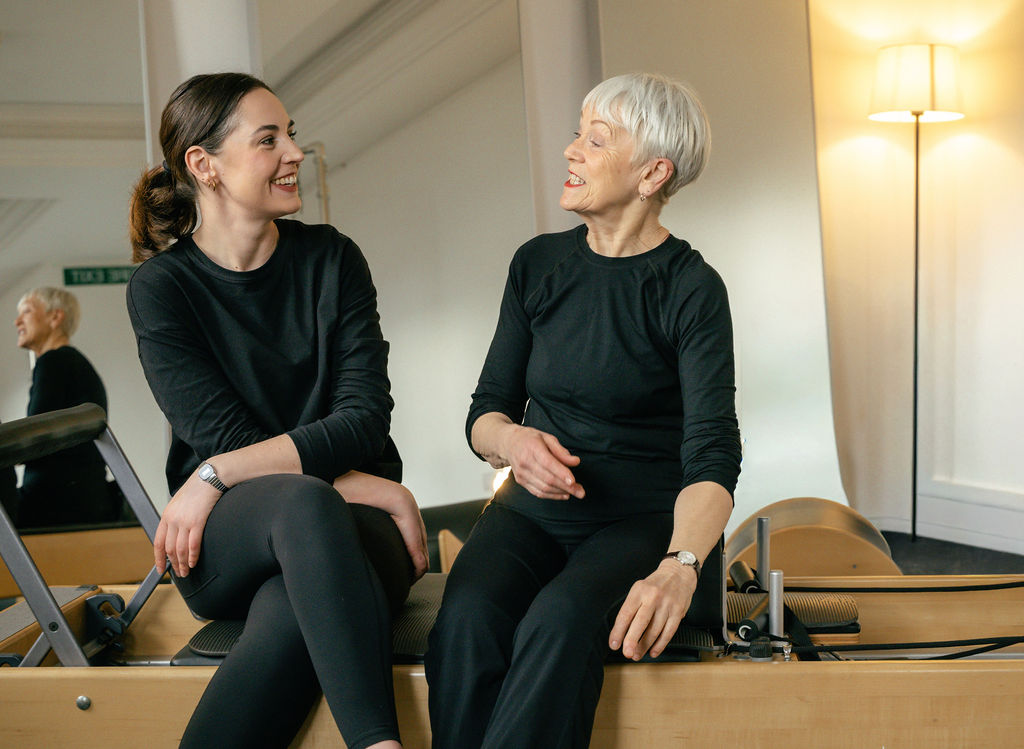 A teacher guiding precise movement in the Pilates studio